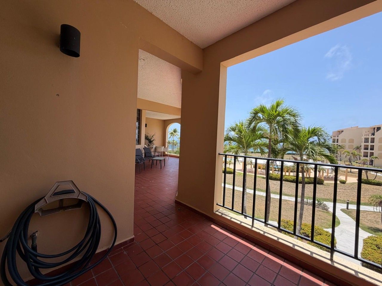 A balcony with a view of palm trees and a building in the background.