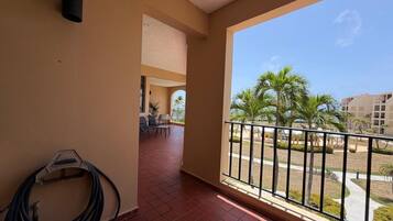 A balcony with a view of palm trees and a building in the background.
