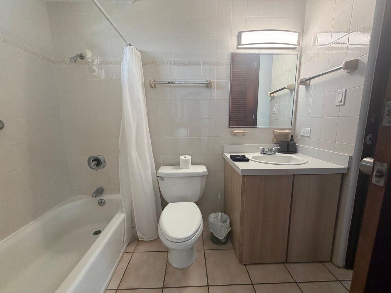 Et badeværelse med badekar, toilet, håndvask og spejl.