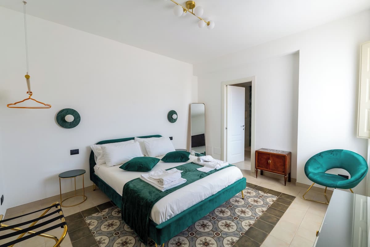 A modern bedroom with a bed, bedside tables, a hanging light fixture, and a mirror.