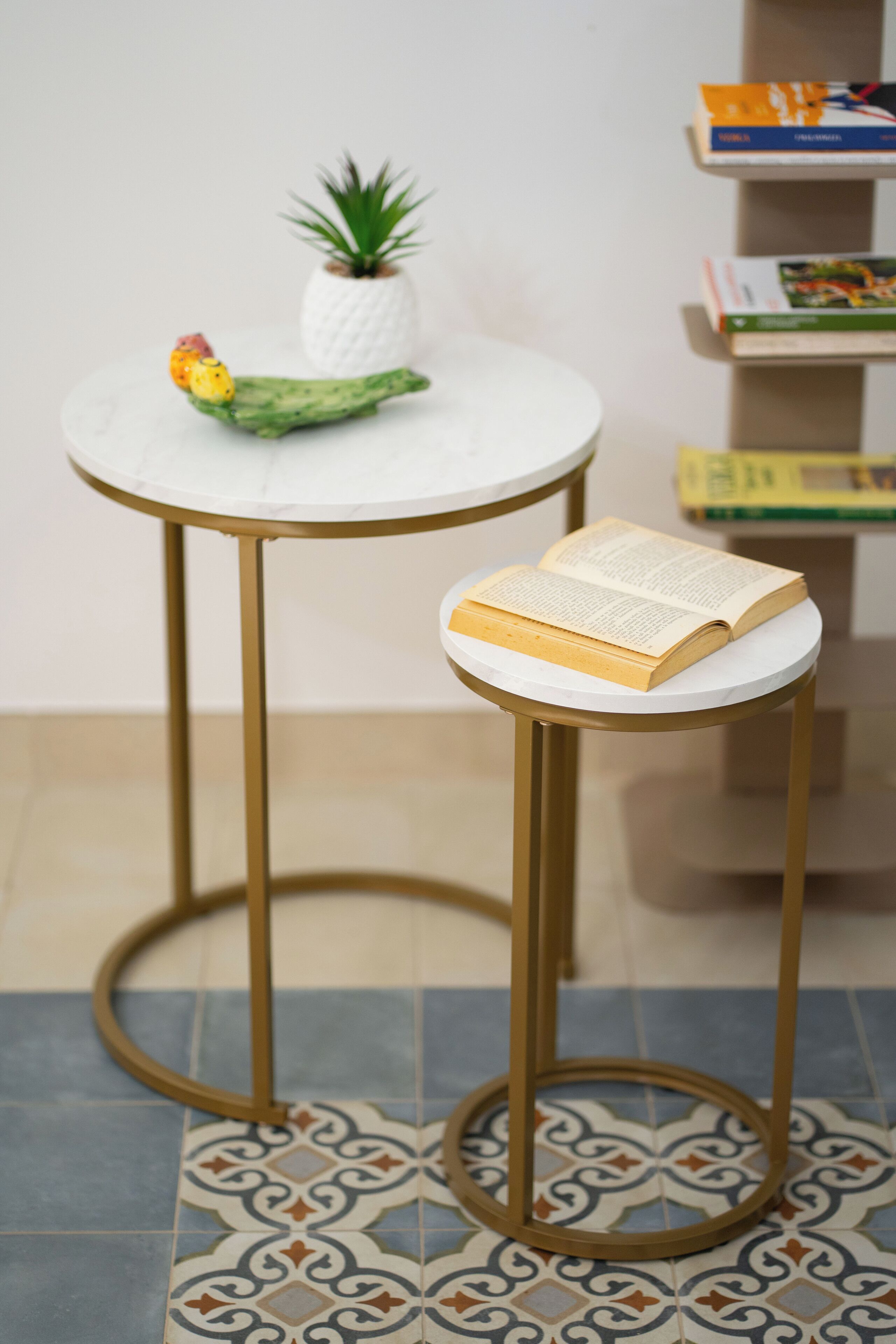 Une petite table ronde avec un plateau blanc et des pieds dorés, accompagnée d’un petit tabouret assorti, avec un plateau blanc et des pieds dorés.
