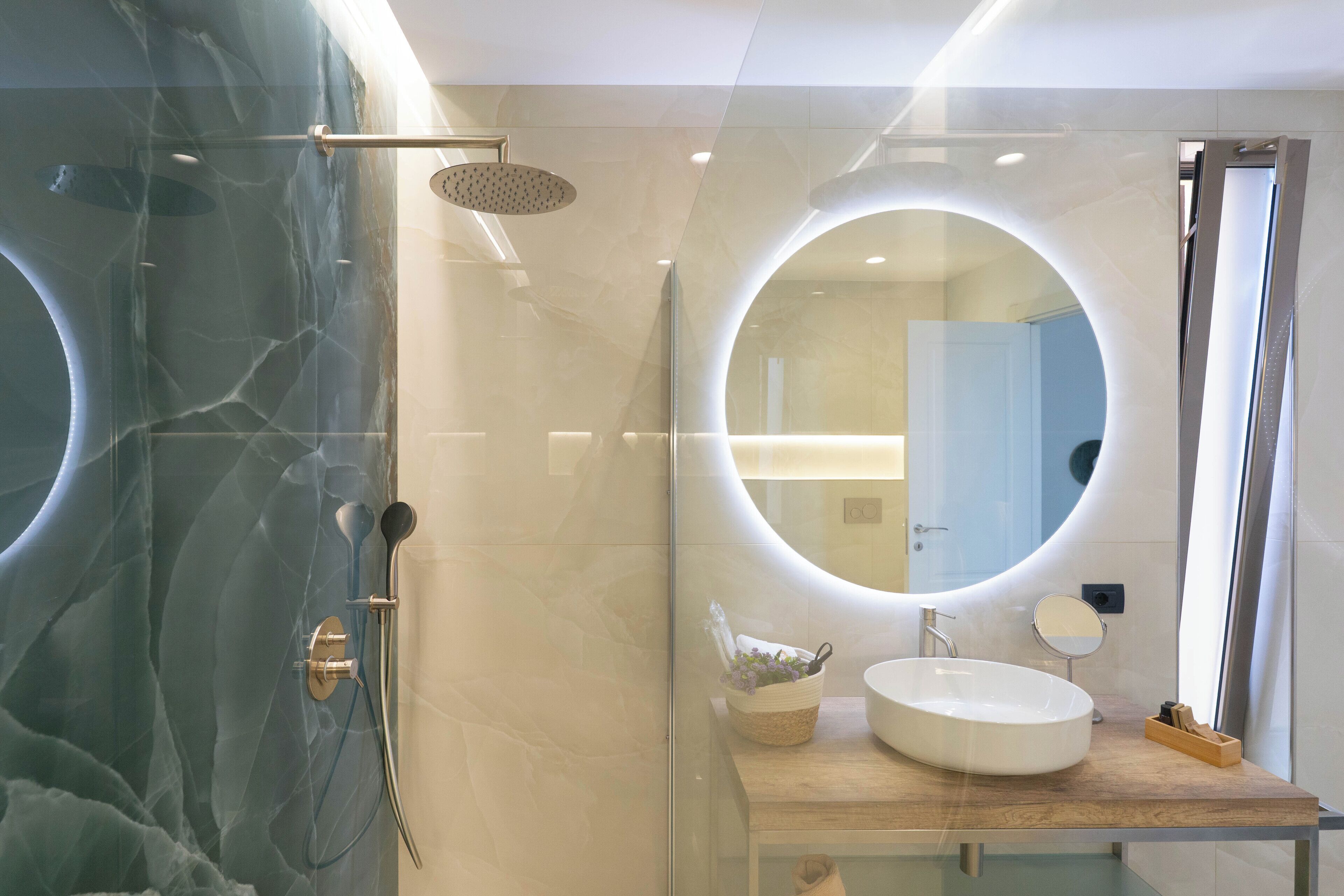 A modern bathroom with a glass-enclosed shower, a wooden vanity with a sink, and a large mirror.