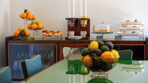Een ontbijtbuffet met sinaasappels, gebak en koffieautomaten.