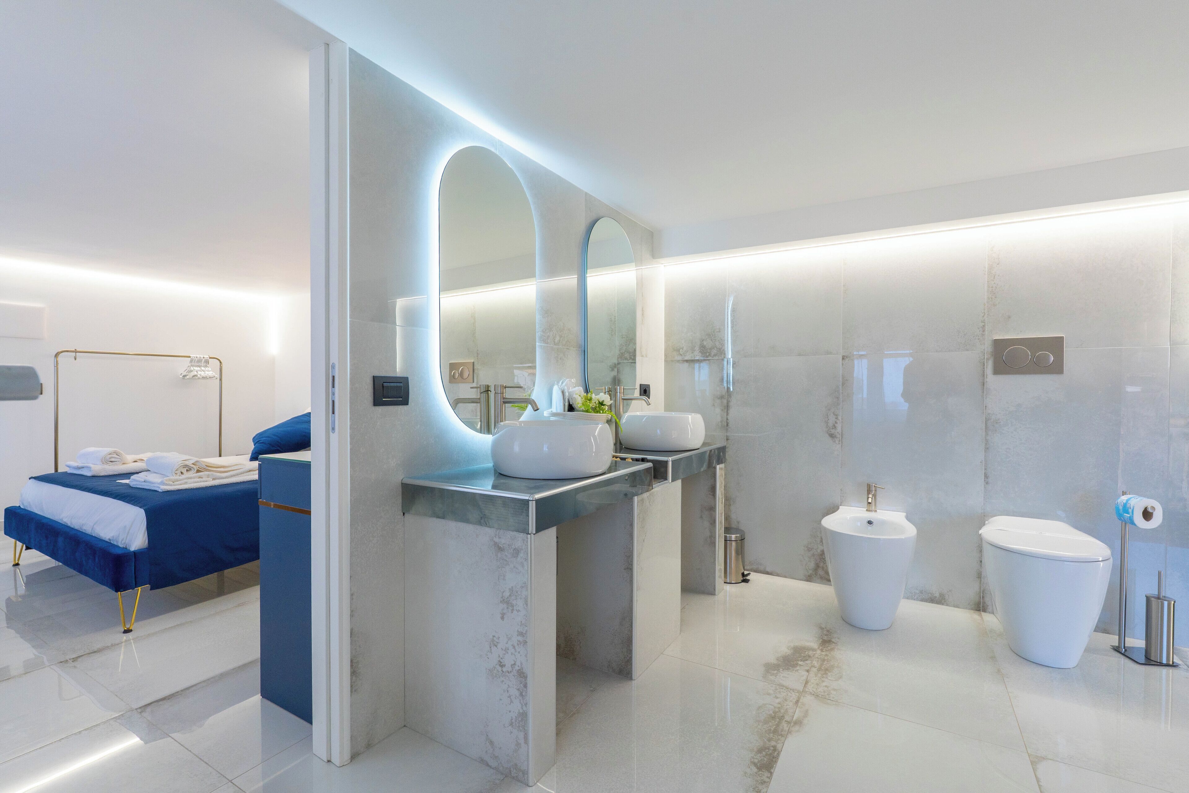 Un baño moderno con cama, un espejo grande, lavabo, bidé e inodoro.