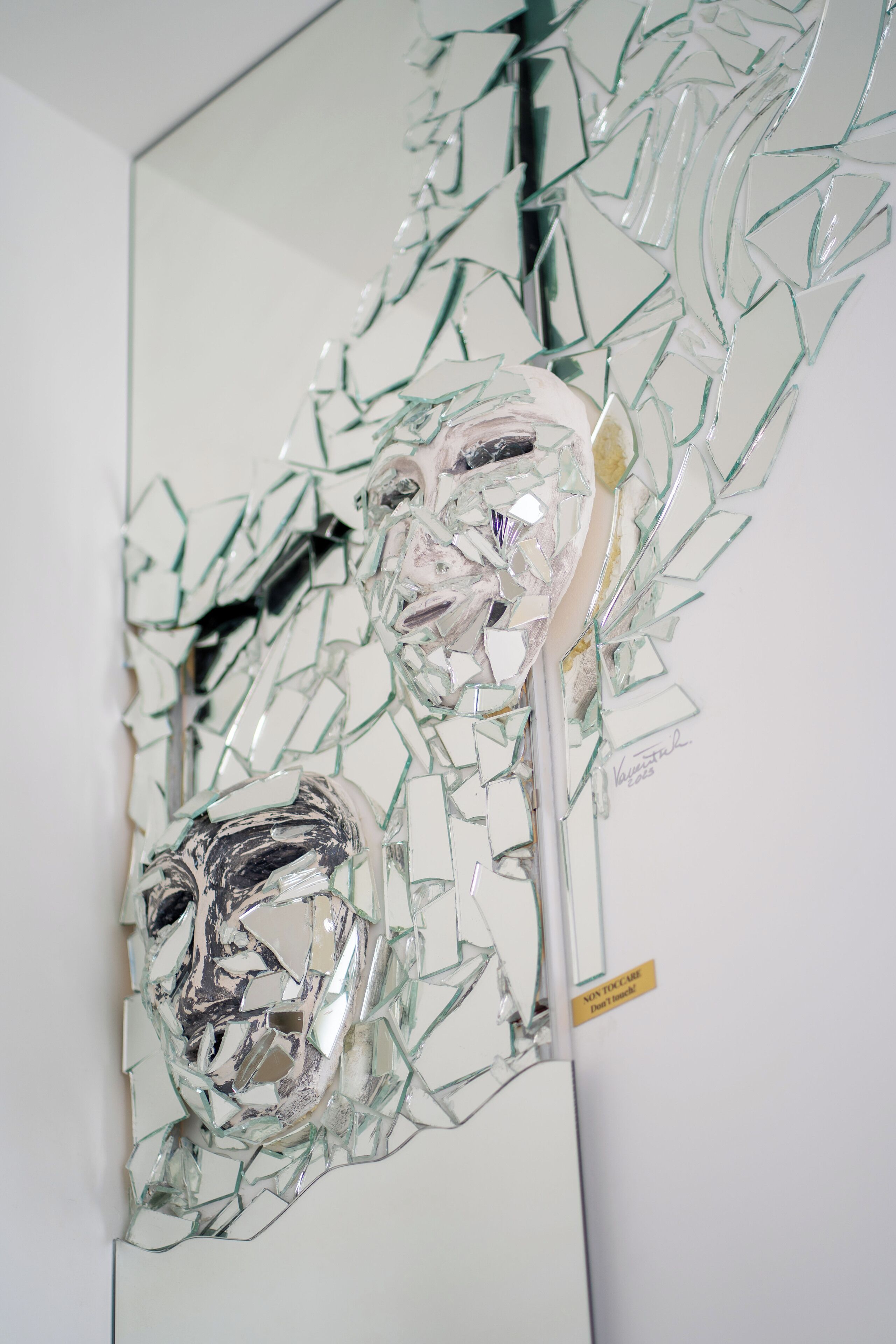 A glass sculpture with a reflective surface and a yellow label.