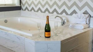 A bathroom with a large bathtub, a bottle of champagne, and two glasses on the counter. - "Sleepover" Hotel Suite with AC/Heating & Indoor Jetted Tub (Big Bear Lake)