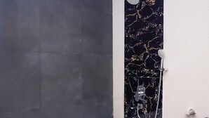 A modern bathroom with a large bathtub, dark tiled walls, and a marble accent wall. - Ravissant Hotel Mandrem (Mandrem)