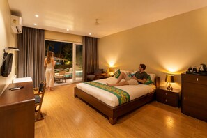 A hotel room with a bed, a desk, a chair, a TV, and a view of a pool. - Ravissant Hotel Mandrem (Mandrem)