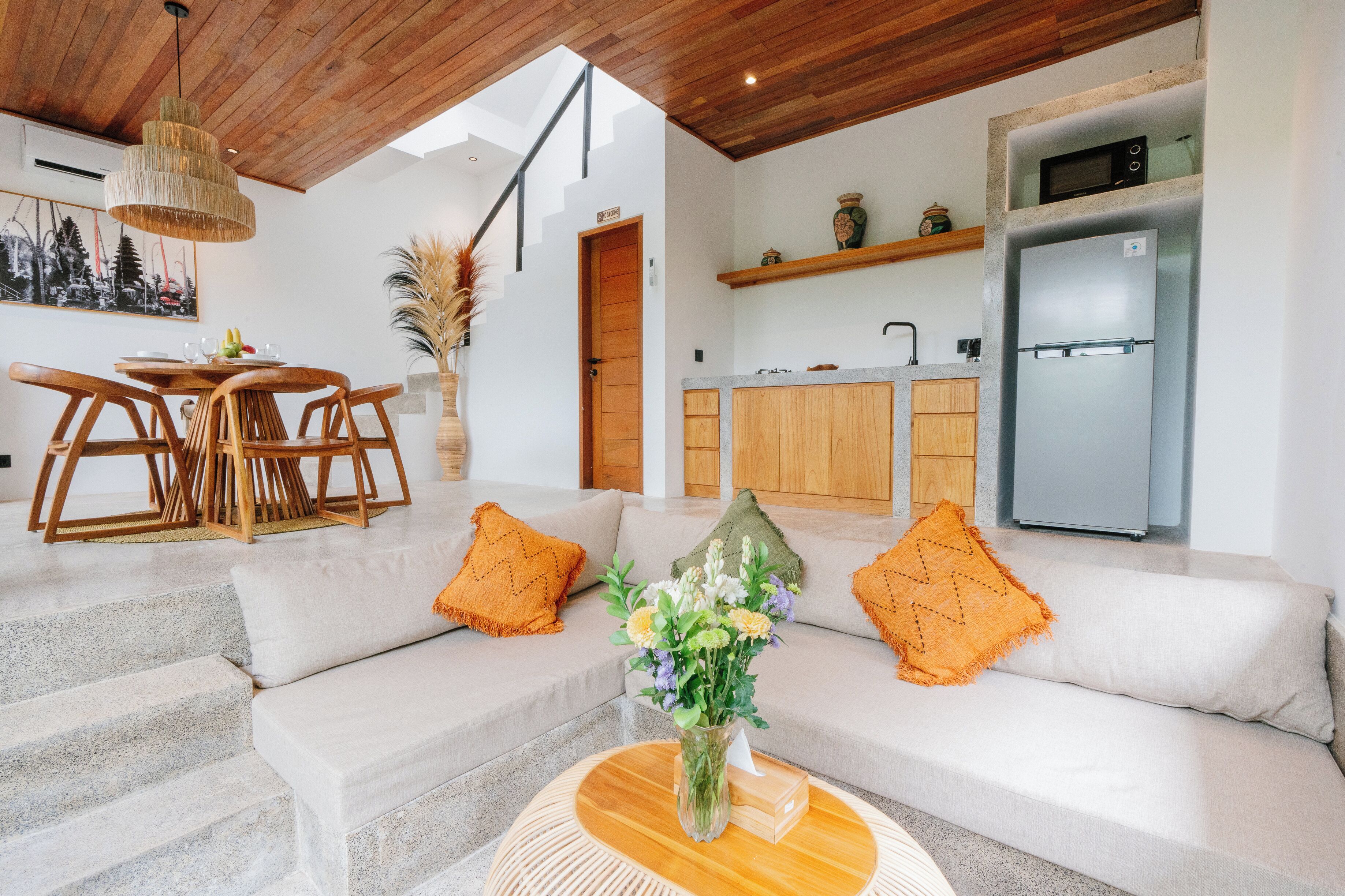 A modern kitchen with a built-in microwave, a stainless steel refrigerator, and wooden cabinets.