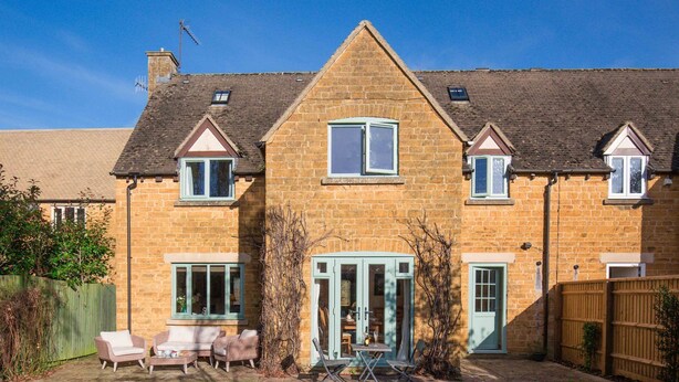 A two-story stone house with a central entrance, a covered patio with outdoor furniture, and a fenced backyard. - fabulous and homely dog friendly holiday cottage  - Kingsley House (Draycott)