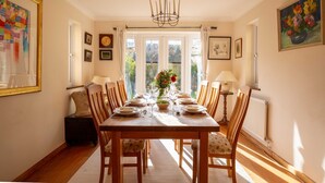 A dining room with a wooden table set for six, surrounded by wooden chairs. - fabulous and homely dog friendly holiday cottage  - Kingsley House (Draycott)