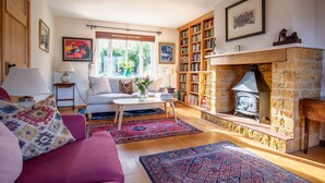 A cozy living room with a fireplace, a sofa, a coffee table, and a bookshelf. - fabulous and homely dog friendly holiday cottage  - Kingsley House (Draycott)