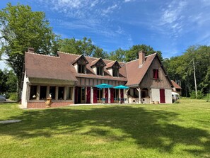 Un grand bâtiment à deux étages, avec une façade en briques, de nombreuses fenêtres et un patio couvert doté d’un espace aménagé pour s’asseoir à l’extérieur.