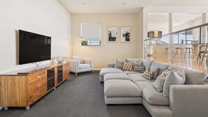 A modern living room with a sectional sofa, a wooden entertainment unit, and a flat-screen TV.