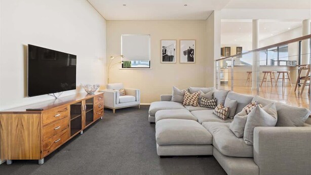 A modern living room with a sectional sofa, a wooden entertainment unit, and a flat-screen TV.