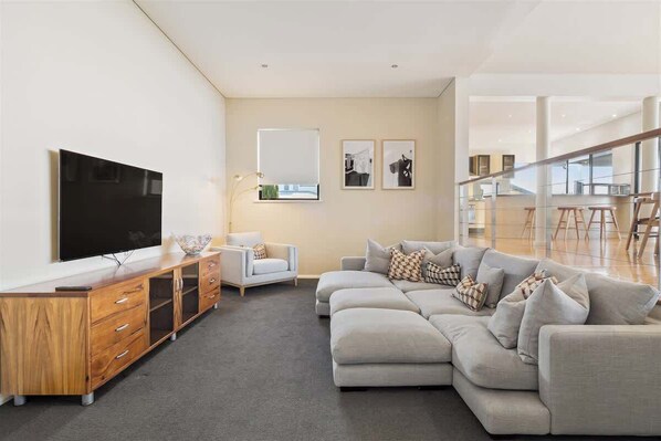 A modern living room with a sectional sofa, a wooden entertainment unit, and a flat-screen TV.
