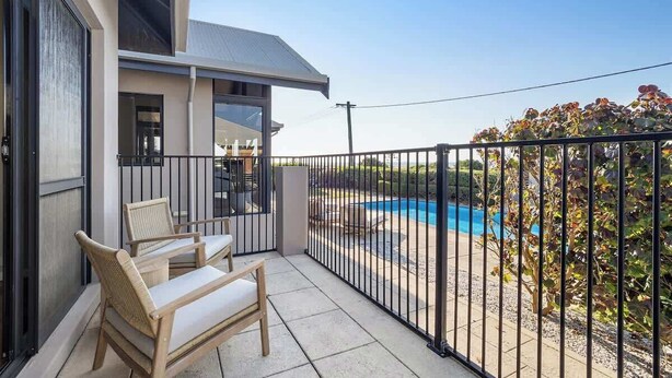 A balcony with a pool view, a chair, and a railing.