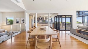 Un amplio espacio de sala con una larga mesa de madera, un sofá y vistas a la cocina y un patio exterior.