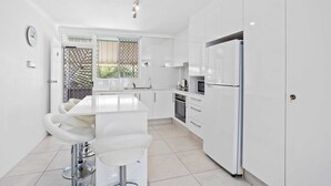 A modern kitchen with white cabinets, a central island, and a refrigerator. - Palm Beach Waterfront Escape (Palm Beach)