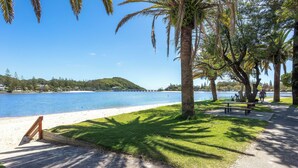 A beachfront park with a concrete path, benches, and palm trees. - Palm Beach Waterfront Escape (Palm Beach)