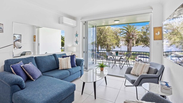 A modern living room with a blue sofa, a round coffee table, and a grey armchair. - Palm Beach Waterfront Escape (Palm Beach)