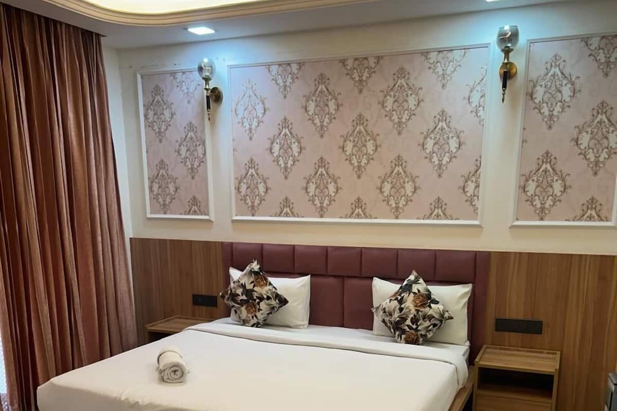 A modern bedroom with a large bed, wooden headboard, and a decorative wall panel.