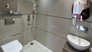 A modern bathroom with a toilet, sink, and shower. - AATITHYAM RESIDENCY (Gurugram)