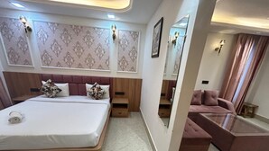 A modern bedroom with a large bed, a sofa, a glass coffee table, and a mirror. - AATITHYAM RESIDENCY (Gurugram)