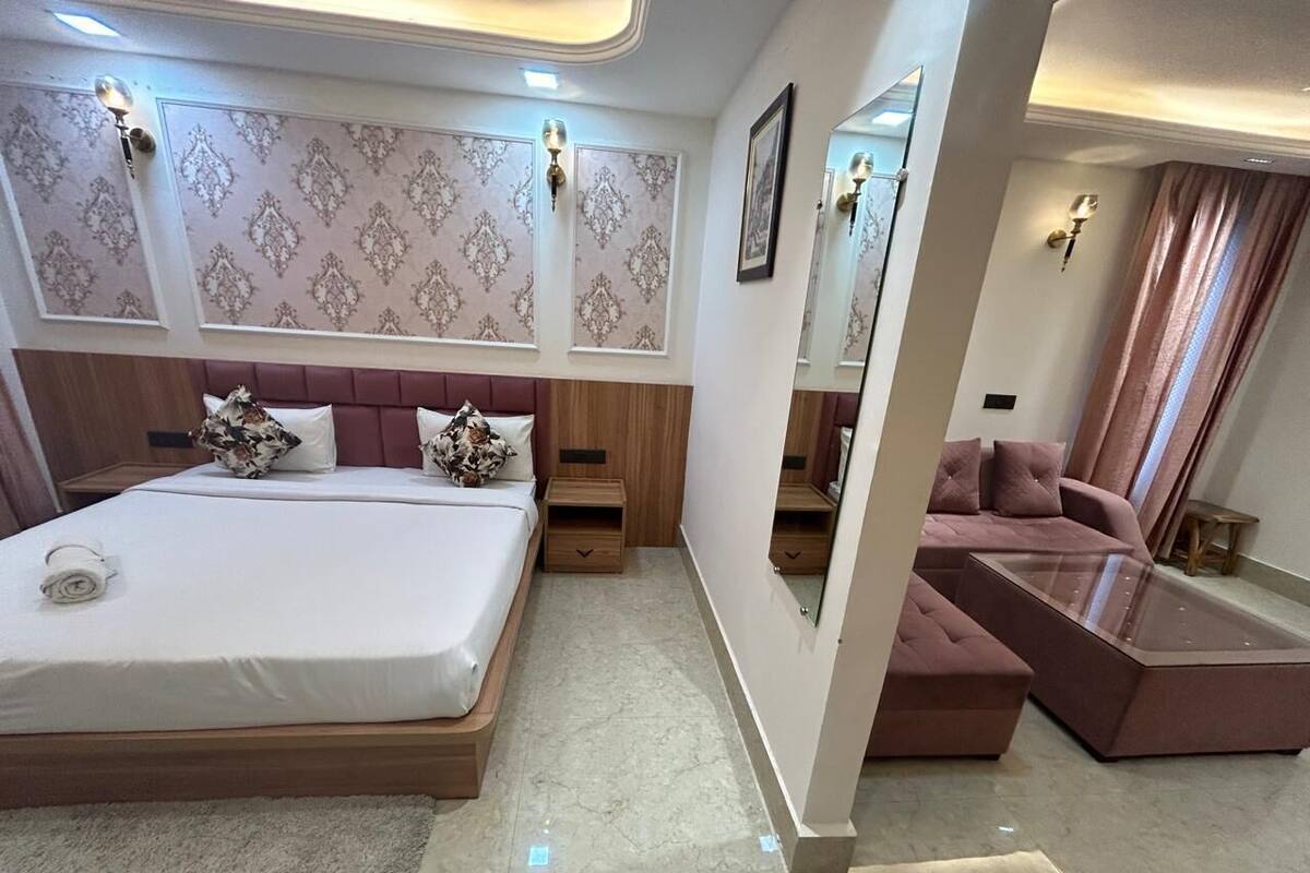 A modern bedroom with a large bed, a sofa, a glass coffee table, and a mirror.