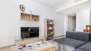 A modern living room with a flat-screen TV, a wooden coffee table, and a grey sofa.