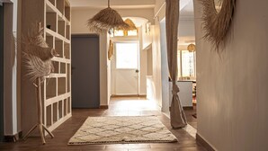 Un couloir avec un lampadaire à pied en fibres tressées, un tapis à motifs et une porte donnant sur une autre pièce.
