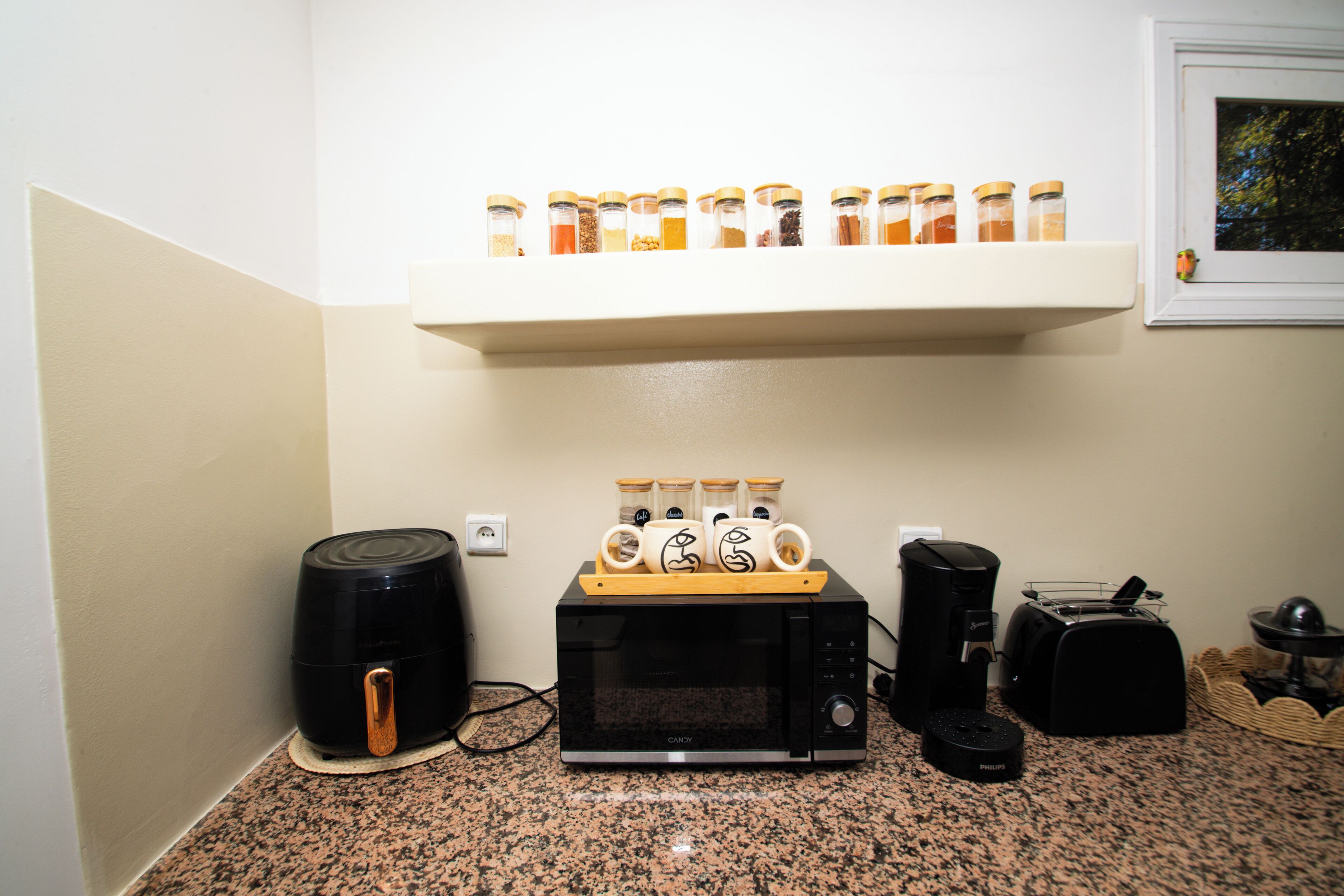 A kitchen with a coffee maker, toaster, and microwave on a granite countertop.