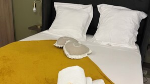 A neatly made bed with white linens, a mustard-colored throw blanket, and decorative pillows. - Lovely studio, ideal for a couple!  (Schoelcher)
