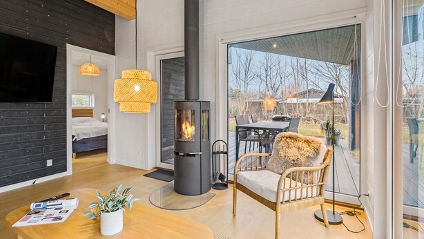 Un interior moderno con chimenea, mobiliario de mimbre y un ventanal con vistas al exterior.