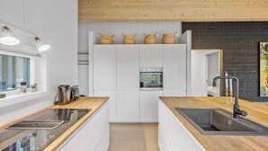 Una cocina moderna con armarios blancos, encimeras de madera, horno empotrado y ventana con vistas.