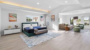 A spacious bedroom with a large bed, a sofa, and a dining area. - Glam Manor | 7,000 Ft Mansion with Waterslide | Sauna | Cold plunge (Sunrise)