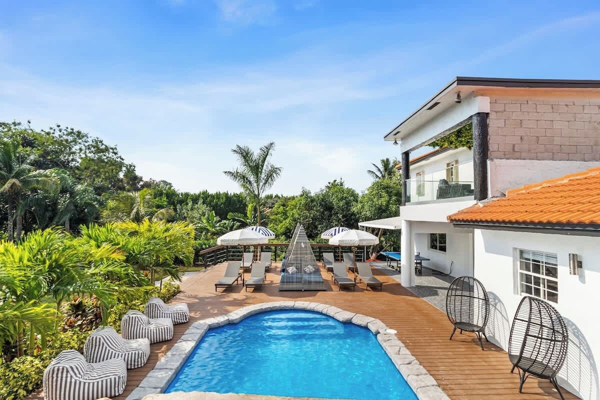 A pool area with lounge chairs, umbrellas, and a clear blue pool.