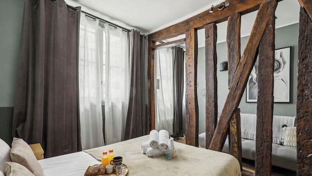 A hotel room with a bed, breakfast tray, towels, and wooden beams. - Suite 332 Brady – Stunning Duplex in Paris 10 (Paris)