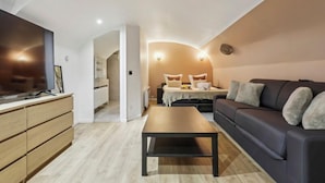 A modern living room with a sofa, a coffee table, and a TV on a wooden cabinet. - Suite 332 Brady – Stunning Duplex in Paris 10 (Paris)