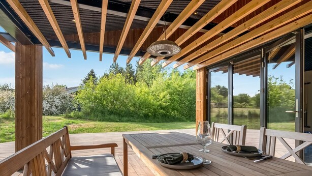 Eine Holzterrasse mit Tisch und Bänken, mit Blick auf eine üppige grüne Landschaft.