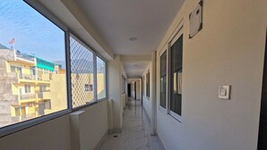 A corridor with a view of a building outside. - Hotel Aastha Height (Rishikesh)