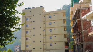 A multi-story residential building with a flat facade, multiple windows, and balconies. - Hotel Aastha Height (Rishikesh)
