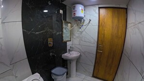 A bathroom with a toilet, bidet, sink, and a shower with a water heater. - Hotel Aastha Height (Rishikesh)