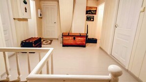 A hallway with a white railing, a suitcase, and a trunk in the background.