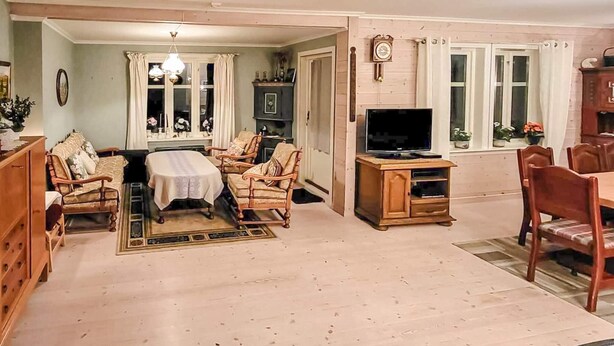 A living room with a sofa set, a dining table, and a television.