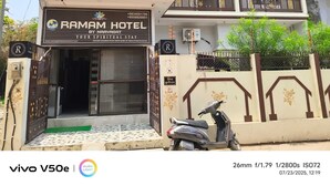 Ein zweistöckiges Gebäude mit einem Schild für das Ramam Hotel by Naavagat, das einen verschlossenen Eingang und einen abgestellten Roller zeigt.