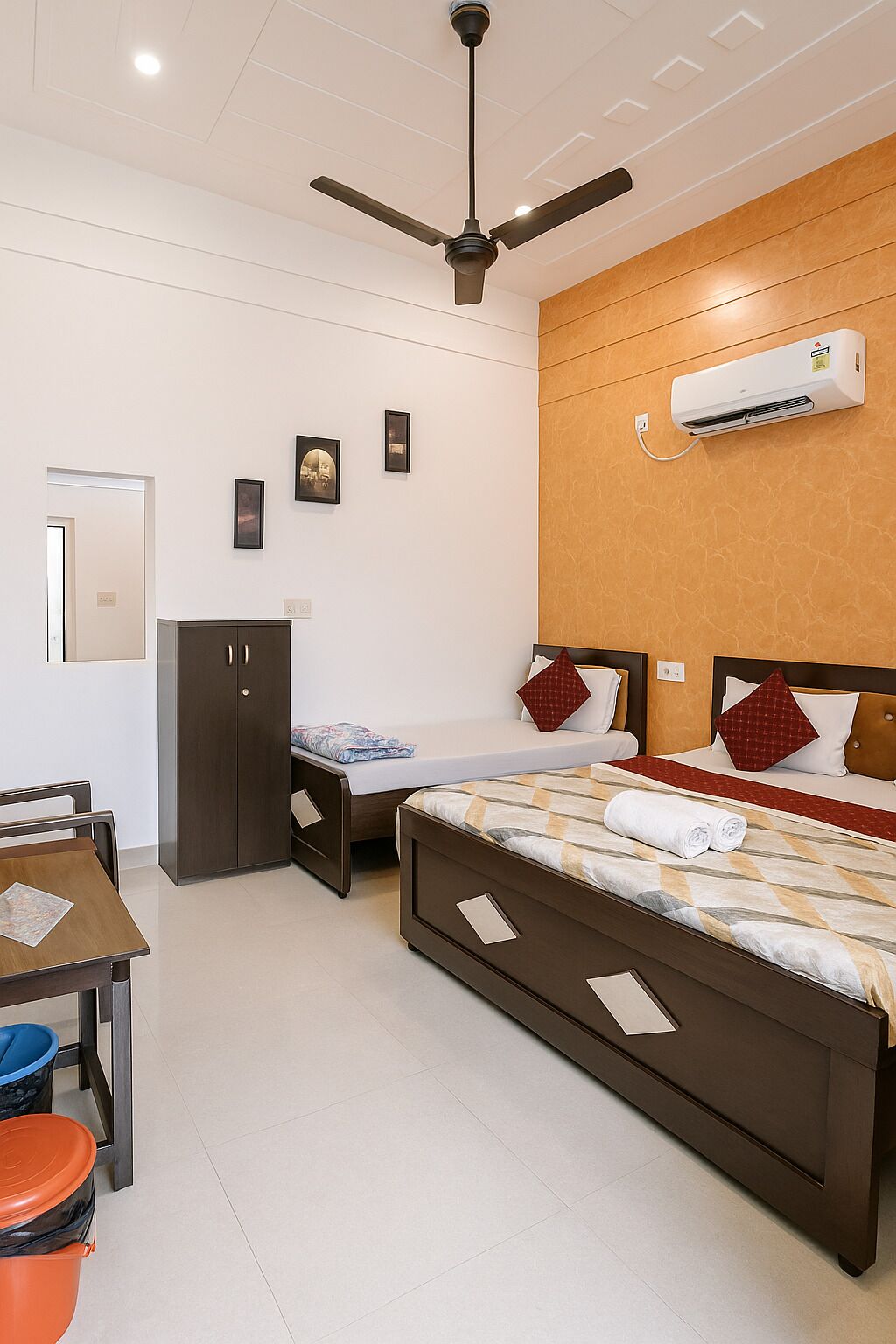 A hotel room with a bed, a desk, a wardrobe, and a ceiling fan.