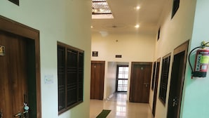 A hallway with wooden doors, a fire extinguisher, and a sign indicating no smoking. - Ramam By Naavagat 700 Meter From Temple (Faizabad)