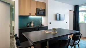 Eine moderne Küche mit Holzschränken, einer schwarzen Arbeitsplatte und einem Essbereich mit Tisch und Stühlen.