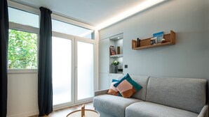 Ein modernes Wohnzimmer mit einem grauen Sofa, einem kleinen runden Tisch und einem Bücherregal.